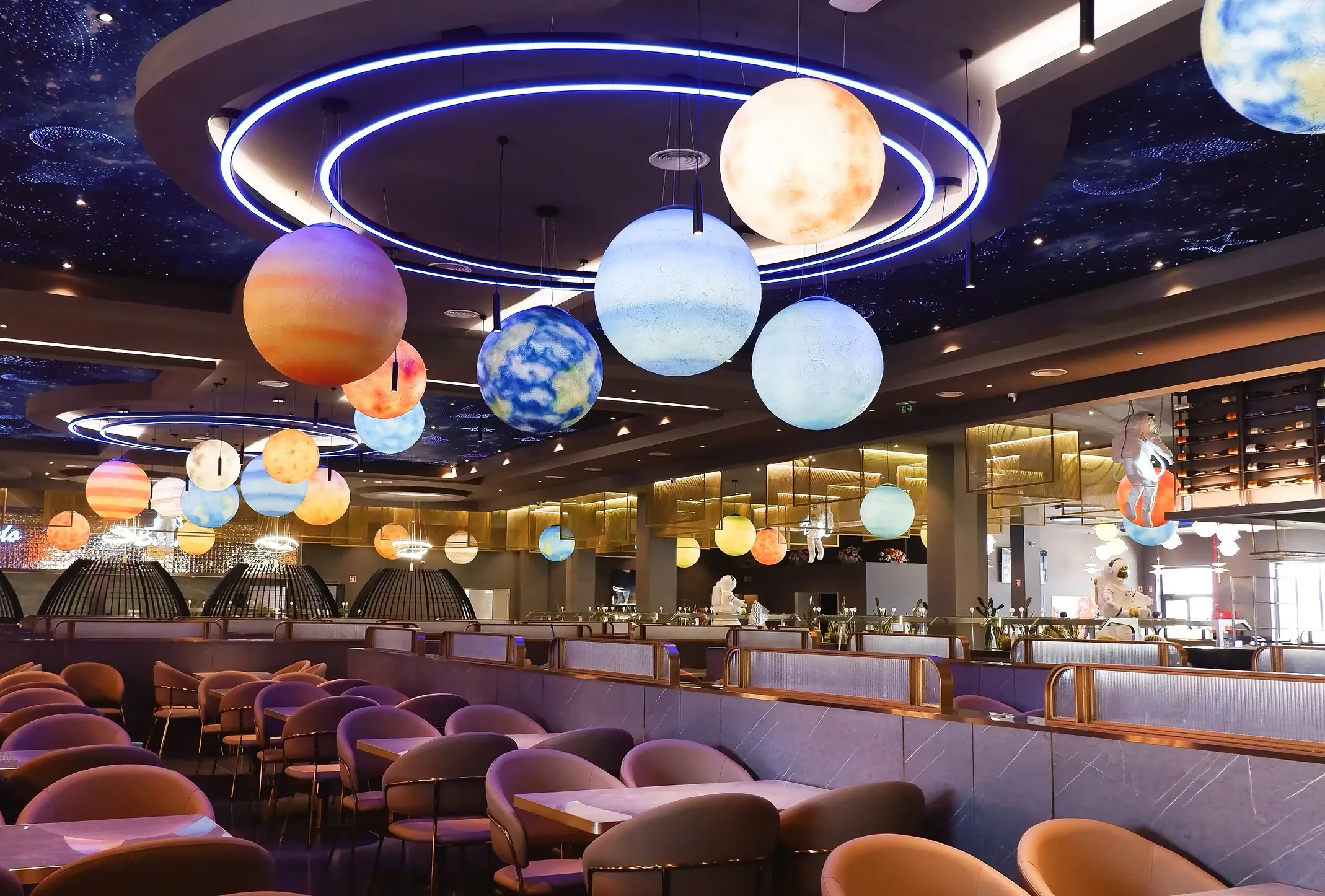 Interior amplo do Star Wok com planetas iluminados, teto estrelado e detalhes em cobre